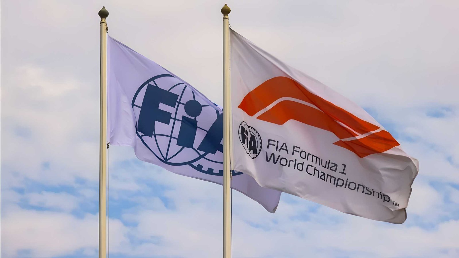 FIA logo and Formula 1 World Championship flags flying on flagpoles against a blue sky
