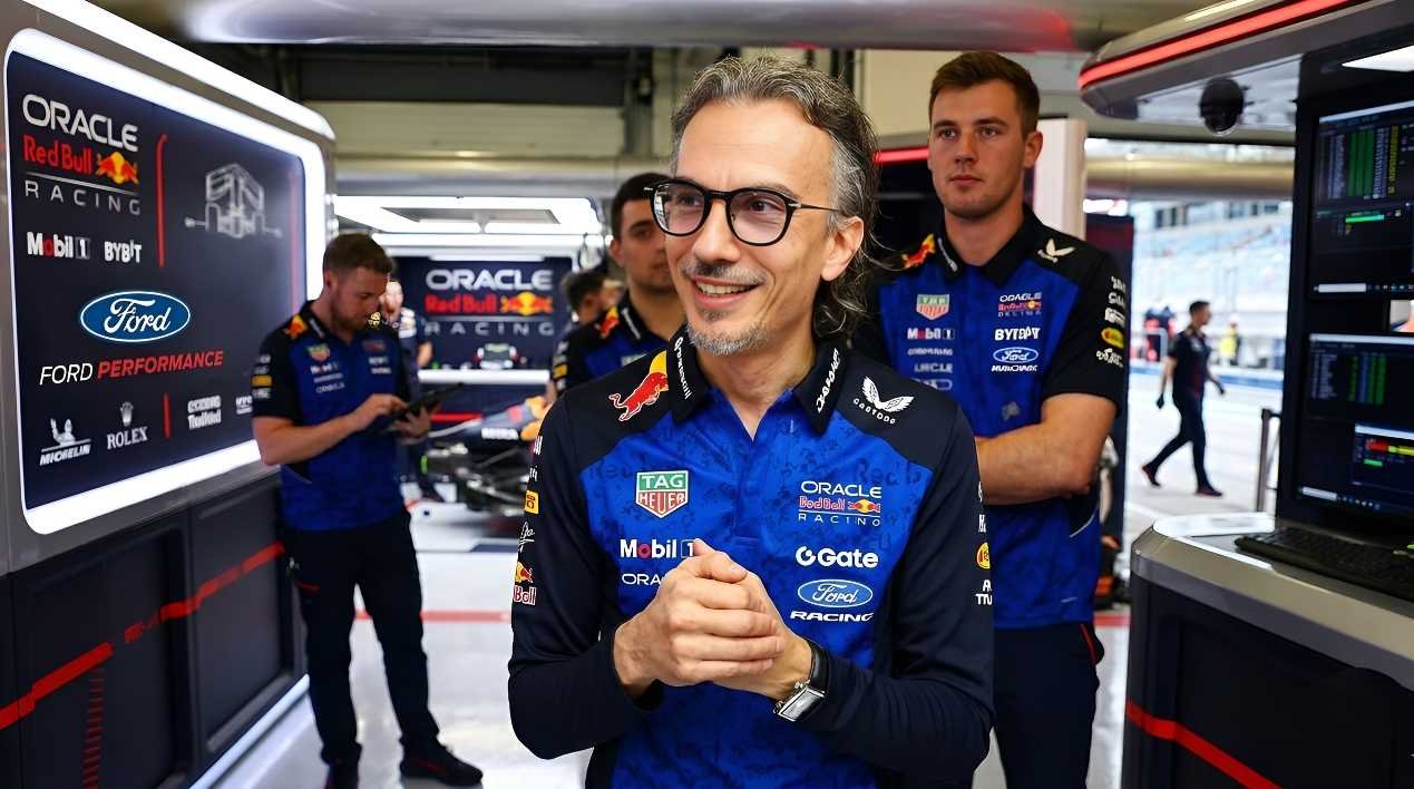 Laurent Mekies wearing Oracle Red Bull Racing team kit, standing in the Formula 1 garage with team personnel and engineering displays in the background