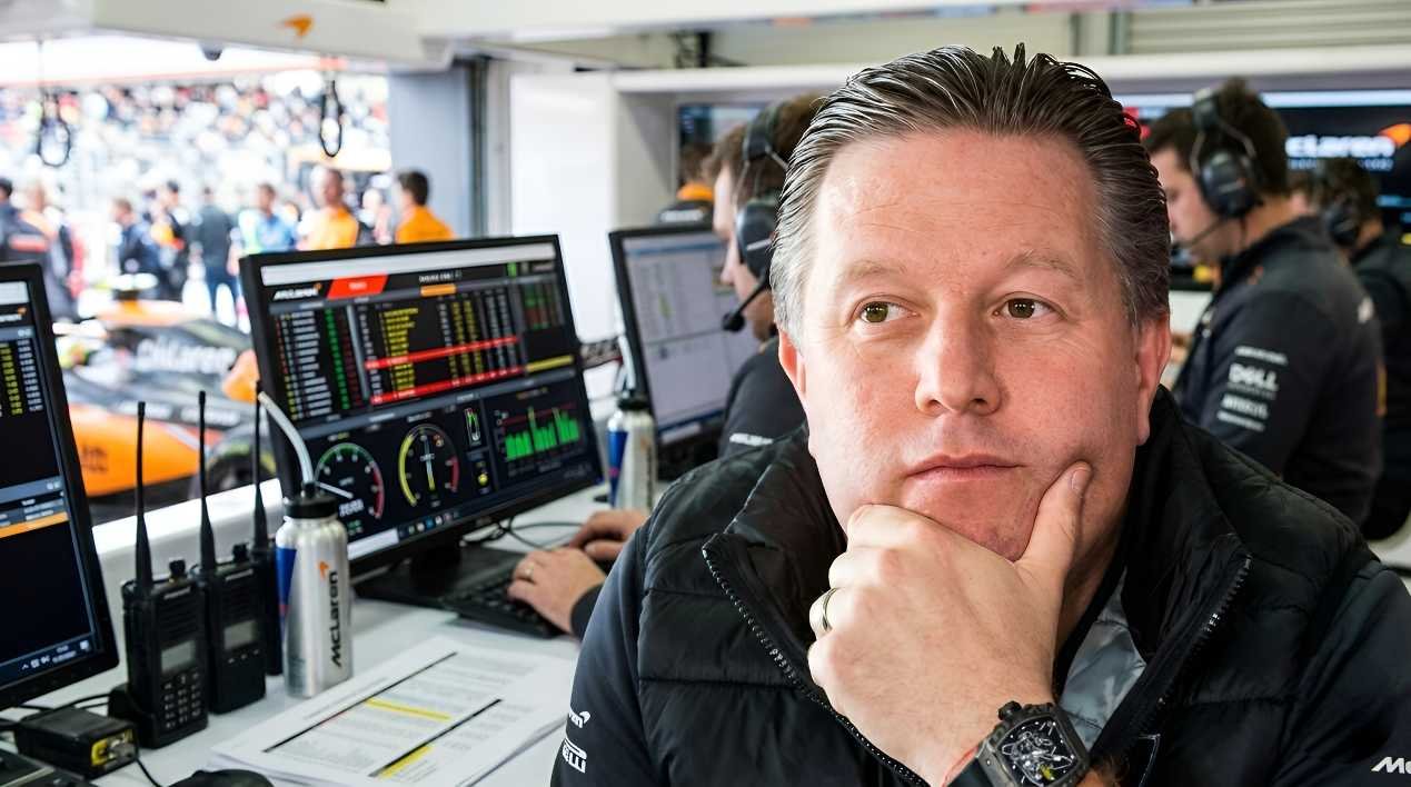 McLaren CEO Zak Brown seated at the pit wall with race telemetry monitors in background